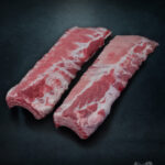 Baby Back Ribs (Kotelettrippen) vom Duroc-Schwein roh auf Steinplatte