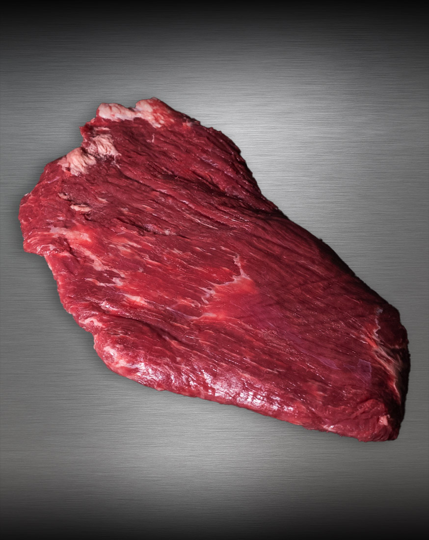 Flanksteak Simmentaler Alpenrind – edel präsentiert, meisterhaft pariert Flanksteak Simmentaler Alpenrind roh – zart marmoriertes Alpenweidefleisch auf gebürstetem Metall, elegant ausgeleuchtet