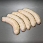 Fläming-Griller Bratwurst roh, grob und charakterstark – handwerklich inszeniert auf kühlem Metallhintergrund