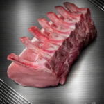 Rohes Schweinekarree vom regionalen Duroc-Schwein am Knochen mit feiner Marmorierung auf neutralem Untergrund.