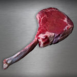 Saftiges Tomahawk Steak Färse vom Wolowina-Rind roh auf kühler Metallplatte