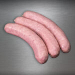 Fläming-Griller gepökelte Bratwurst, fein glänzend und zartrosa auf gebürstetem Metall – Sinnbild reinen Genusses