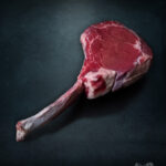 Saftiges Tomahawk Steak Färse vom Wolowina-Rind roh auf kühler Metallplatte