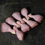 Chicken Drumsticks vom deutschen Hähnchen, auf Schneidebrett mit Kräutern