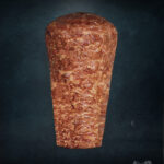 Berliner Döner Kebab Spieß aus handgeschichtetem Hähnchenfleisch, roh und mariniert auf dunkler, edler Unterlage präsentiert.