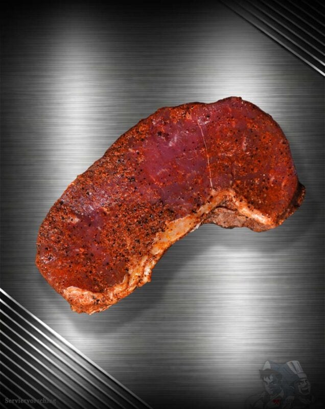Rumpsteak vom Black Angus, kräftig mit Smoky-Pepper-Gewürz veredelt, auf einer metallischen Oberfläche präsentiert.