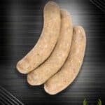 Grobe Wildbratwurst aus regionaler Jagt: drei leicht gebogene Bratwürste nebeneinander auf dunklem Hintergrund.