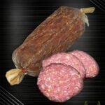 Rehsalami aus deutschem Wildfleisch als ganze, dunkelbraune Salami mit zwei angeschnittenen Scheiben auf schwarzem Hintergrund.